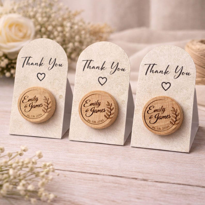 Three wooden nameplate magnets with the names 'Emilly & James' engraved on them, placed on a wooden surface.