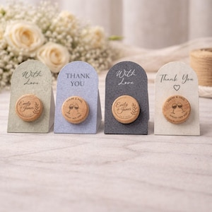 four small, wooden cork holders with wine bottle caps attached to them. Each holder has a different message written on it, including "With Love", "Thank You", "Thank You with Love", and "Thank You". The holders are arranged in a row, with the first one on the left and the last one on the right.