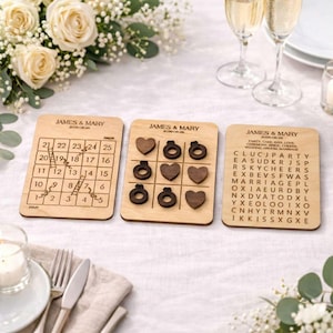 three wooden coasters or game pieces with text and numbers on them, placed on a table with a floral arrangement and wine glasses.