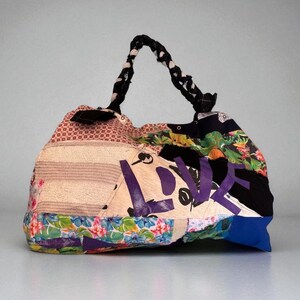 May include: A patchwork tote bag with a braided handle. The bag features a variety of fabric patterns, including floral, striped, and geometric designs. The word "LOVE" is prominently displayed in purple letters on the front.
