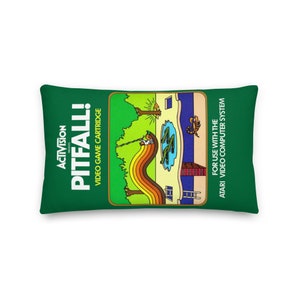 Könnte beinhalten: Grünes Kissen mit einem Retro-Videospiel-Kartuschen-Design. Das Bild zeigt den Text "Activision Presents Pitfall!" und "Video Game Cartridge". Die Spielkassette ist für das Atari Video Computer System.