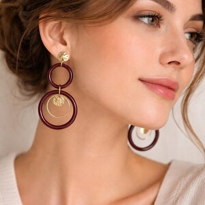 Peut inclure: Boucles d'oreilles créoles bordeaux et dorées. Les boucles d'oreilles présentent un clou doré, un cercle bordeaux et un disque doré. Ces boucles d'oreilles sont une pièce de caractère, ajoutant une touche d'élégance à n'importe quelle tenue.