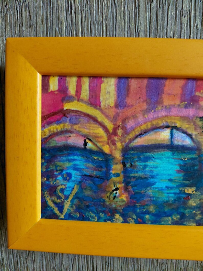 K&ouml;nnte beinhalten: Abstrakte Malerei in einem gelben Rahmen. Das Kunstwerk zeigt eine gesichts&auml;hnliche Komposition mit blauen, gelben, rosa und violetten Farbt&ouml;nen. Das Gem&auml;lde hat ein strukturiertes Aussehen mit sichtbaren Pinselstrichen und einer Signatur in der unteren linken Ecke.