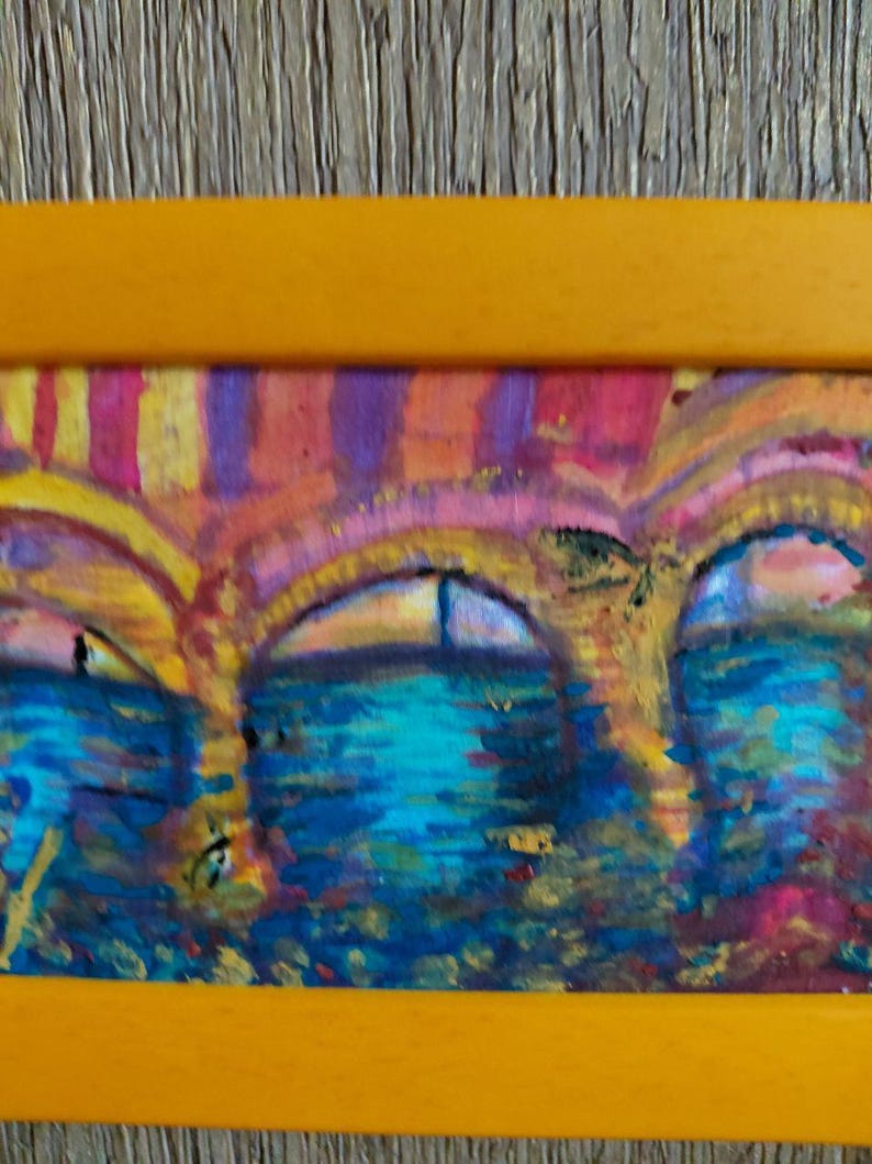 K&ouml;nnte beinhalten: Abstrakte Malerei einer Br&uuml;cke mit bogenf&ouml;rmigen &Ouml;ffnungen, in einem gelben Rahmen. Das Kunstwerk zeigt eine farbenfrohe Darstellung der Br&uuml;cke und des Wassers, mit Blau-, Rosa- und Gelbt&ouml;nen.