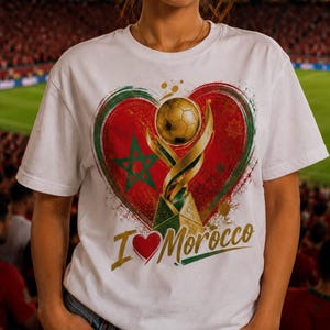 Peut inclure: Un t-shirt blanc à manches courtes avec un motif représentant un trophée de football doré au centre d'un cœur aux couleurs rouge et verte avec une étoile verte. Le texte "I [symbole cœur] Morocco" est imprimé en doré et vert sous le cœur.