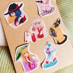 Può includere: Sei adesivi colorati con personaggi in stile anime. Gli adesivi sono stampati su carta bianca e hanno una finitura lucida. I personaggi sono disegnati in una varietà di pose ed espressioni.