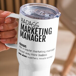 May include: White travel mug with a black inscription that reads "BADASS MARKETING MANAGER noun like a regular marketing manager except way more badass see also: superhero, miracle worker"