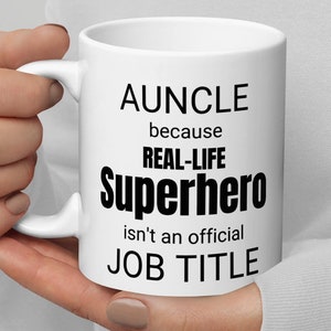 May include: White ceramic mug with black text that reads "AUNCLE because REAL-LIFE SUPERHERO isn't an official JOB TITLE"