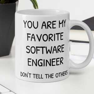 May include: White ceramic mug with black text that reads "You are my favourite software engineer. Don't tell the others."