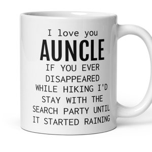 May include: White ceramic coffee mug with black text that reads "I love you AUNCLE IF YOU EVER DISAPPEARED WHILE HIKING I'D STAY WITH THE SEARCH PARTY UNTIL IT STARTED RAINING"