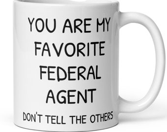 May include: White ceramic coffee mug with black text that reads "You are my favorite federal agent. Don't tell the others."