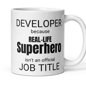 Peut inclure: Mug en céramique blanche avec du texte noir qui dit "DEVELOPER because REAL-LIFE Superhero isn't an official JOB TITLE".