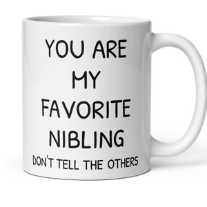 May include: White ceramic coffee mug with black text that reads "You are my favourite nibling. Don't tell the others."
