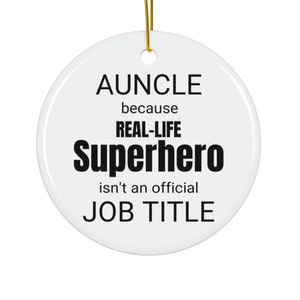 May include: White ceramic bauble with black text that reads "AUNCLE because REAL-LIFE Superhero isn't an official JOB TITLE".