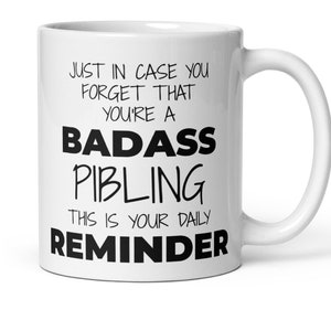 May include: White ceramic coffee mug with black text that reads "Just in case you forget that you're a badass sibling. This is your daily reminder."