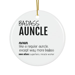 Puede incluir: Adorno de cerámica blanca con el texto "BADASS AUNCLE" en negro. El texto "nombre" está debajo, seguido de la definición: "como un tío normal, excepto mucho más badass". El texto "ver también" está debajo, seguido del texto "superhéroe, hacedor de milagros".