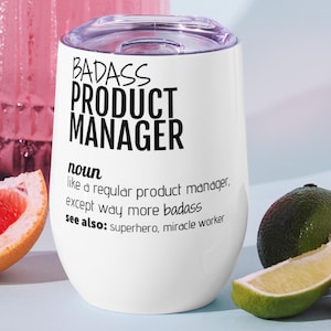 Peut inclure: Gobelet à vin sans pied blanc avec un couvercle transparent, avec le texte "BADASS PRODUCT MANAGER". Le gobelet est entouré d'une tranche de pamplemousse, de citron vert et de fraise. Le texte définit un chef de produit comme un super-héros et un faiseur de miracles.