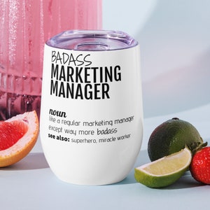 May include: White stainless steel wine tumbler with a black inscription that reads "BADASS MARKETING MANAGER noun like a regular marketing manager except way more badass see also: superhero, miracle worker".