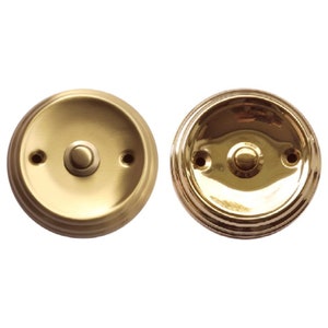 May include: Two round, polished brass doorbells with a single button in the center. The doorbells have a raised, decorative rim.