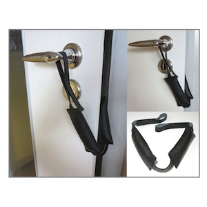 Könnte beinhalten: Ein schwarzer Türgurt mit gepolsterten Griffen zum Trainieren zu Hause. Der Gurt ist an einem Türgriff befestigt und liegt auch flach.