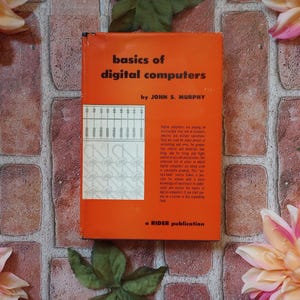 Puede incluir: Un libro de color naranja brillante titulado Basics of Digital Computers de John S. Murphy, una publicación de Rider. La portada presenta un gráfico rectangular blanco con una ilustración de ábaco negra y un bloque de texto descriptivo en fuente negra.