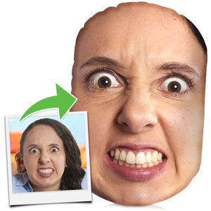 May include: A close-up of a face cushion featuring a woman's face printed on it. The woman has a surprised expression with her eyes wide open and her mouth slightly open. The cushion is white and has a soft, plush texture.