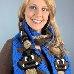 May include: A blue and brown crocheted scarf with a pixelated mushroom design.