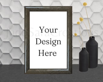 May include: A black framed picture with a white background and the text "Your Design Here". The picture is sitting on a gray surface with two black vases and dried yellow flowers.