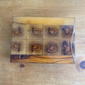 Op de afbeelding: Een houten doos met een schaakbordpatroon en een decoratief ontwerp van cirkels. De doos is gemaakt van licht en donker hout.