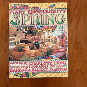 May include: A hardcover book titled "MARY ENGELBREIT'S SPRING" with a colorful floral and interior design cover. The book is written by Charlotte Lyons and photographed by Barbara Elliott Martin.