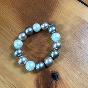 May include: A bracelet made of alternating silver and white beads. The bracelet is made of round beads and is approximately 7 inches in length.