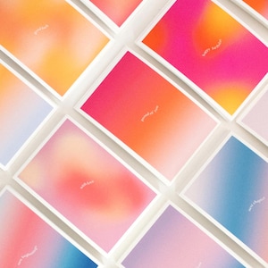 Könnte beinhalten: Eine Sammlung rechteckiger Grußkarten mit lebendigen, weich gezeichneten Farbverlaufshintergründen in Rosa, Orange, Gelb und Blau. Jede Karte zeigt kleinen, weißen, zentrierten Text mit Phrasen wie good luck, happy birthday, proud of you, with love, new chapter und new beginnings.