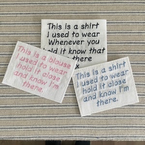 May include: Three white fabric patches with embroidered text. The top patch reads "This is a shirt I used to wear Whenever you hold it know that there". The middle patch reads "This is a blouse I used to wear hold it close and know I'm there.". The bottom patch reads "This is a shirt I used to wear hold it close and know I'm there."