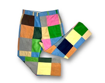 May include: Patchwork pants made from different colored fabrics, including blue, green, pink, yellow, and brown. The pants are folded in half, with the legs overlapping.