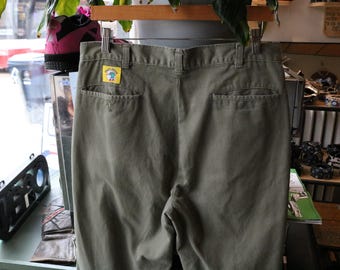 Calça Duck-Head | Calça chino vintage dos anos 90, verde-oliva com pregas frontais e etiqueta com o logotipo | Roupa de trabalho casual clássica