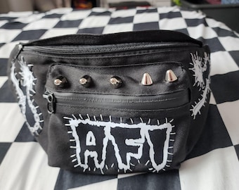 May include: A black bum bag featuring a white embroidered patch with the text AFI, four silver-toned metal cone studs above a zippered front pocket, and white embroidered chain-link designs on the left and right sides of the bag.
