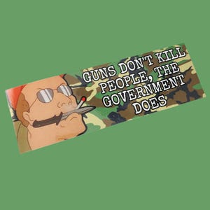 May include: A green, brown and black camouflage sticker with the text "Guns Don't Kill People, The Government Does". A cartoon character with a cigarette and a knife is in the background.