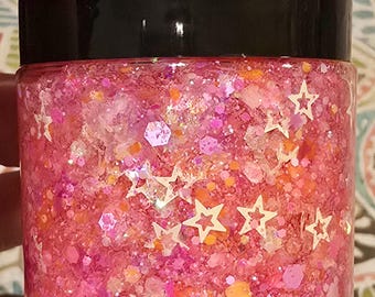 May include: A small clear jar filled with pink glitter and white star-shaped glitter. The jar has a black lid.