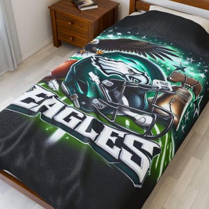 May include: A black and green bedspread featuring the Philadelphia Eagles football team logo. The design includes a football helmet, an eagle, and the word "EAGLES" in large white letters. The background has a green and black gradient.