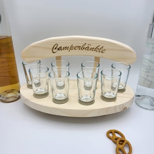 Könnte beinhalten: Holz-Schnapsglashalter mit dem eingravierten Text "Camperbänkle" auf der Oberseite. Der Halter hat acht Schnapsgläser und steht auf einer weißen Oberfläche.