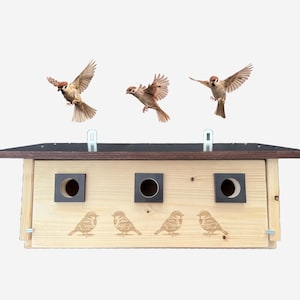 Könnte beinhalten: Ein Vogelhaus aus Holz mit drei Nistfächern und einem schwarzen Dach. Das Vogelhaus ist braun gebeizt und mit vier Spatzen-Silhouetten verziert. Drei Spatzen fliegen in der Luft über dem Vogelhaus.