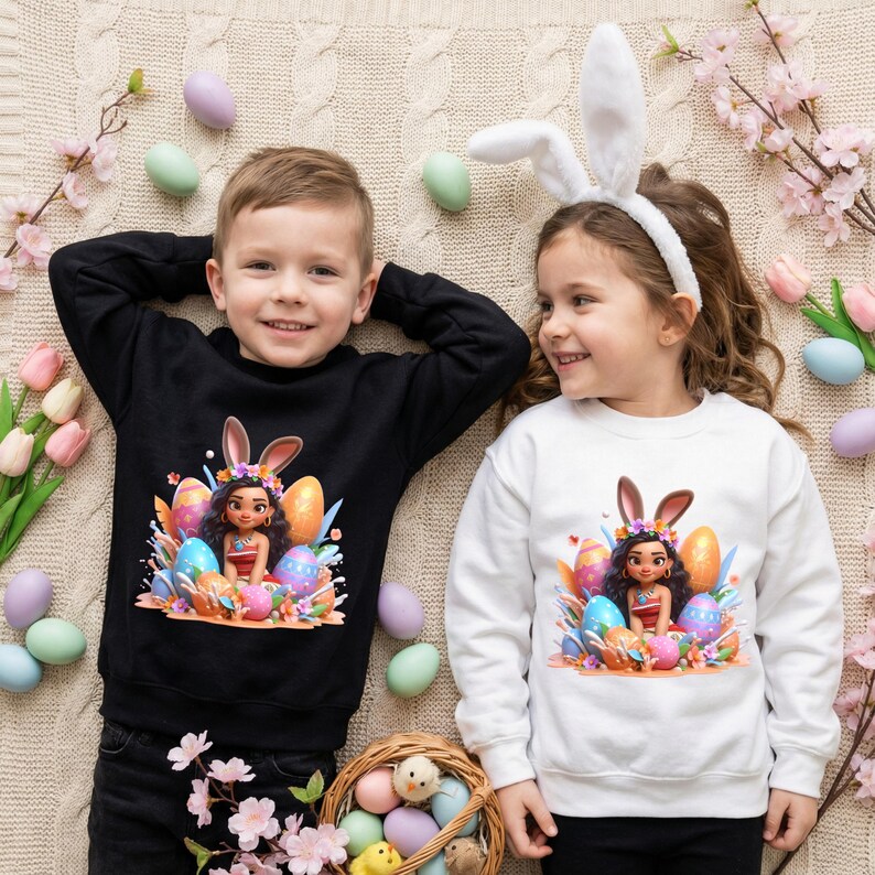 May include: Two children wearing Easter-themed sweatshirts. One child wears a black sweatshirt, the other a white one. Both sweatshirts feature a graphic of a girl with bunny ears and colorful Easter eggs. The children are smiling.