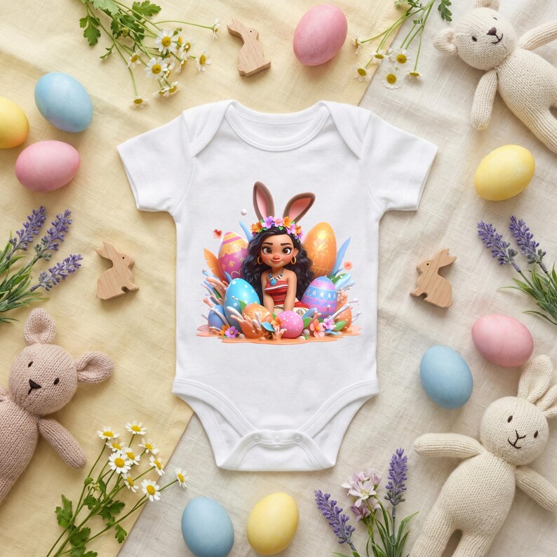 May include: White baby onesie featuring a colorful graphic of a girl with bunny ears surrounded by Easter eggs. The onesie is surrounded by pastel-colored Easter eggs, wooden bunnies, and stuffed animal bunnies.