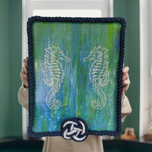 scale view of original seahorse painting held in hands shows 16x20 size nautical rope frame mixed media coastal art blue green wall decor statement piece