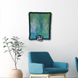 coastal wall decor mockup shows original nautical seahorse painting displayed above chair blue green wall art with rope frame for beach house style