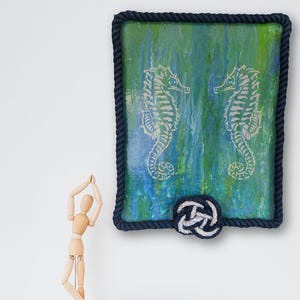 small shelf vignette with original seahorse painting blue green poured background rope frame border nautical wall art for coastal cottage decor