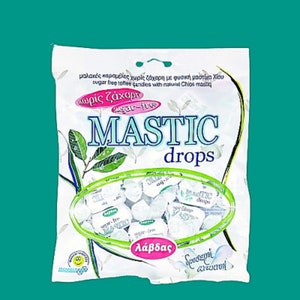 Könnte beinhalten: Eine weiße Tüte zuckerfreier Mastix-Tropfen mit grünem Blattdesign. Die Tüte trägt die Aufschrift "Mastic Drops" in blauen und grünen Buchstaben. Die Tüte trägt auch die Aufschrift "χωρίς ζάχαρη" und "sugar-free" in rosa Buchstaben.