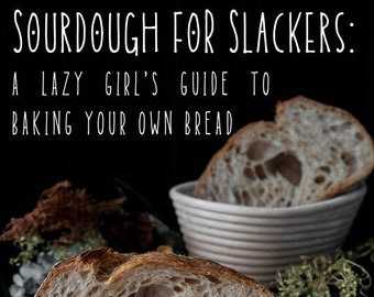 Puede incluir: Un primer plano de una hogaza de pan de masa madre cortada por la mitad, revelando una miga de color marrón claro con grandes burbujas de aire. El pan está apoyado sobre un paño de lino blanco y una tabla de cortar de madera. El texto "SOURDOUGH FOR SLACKERS: A LAZY GIRL'S GUIDE TO BAKING YOUR OWN BREAD BY NASTASSIA COFFMAN" es visible en la parte superior de la imagen.
