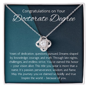 May include: A silver necklace with a pendant featuring a central clear stone surrounded by smaller stones. The necklace is presented in a gift box with the text "Congratulations on Your Doctorate Degree" and a motivational message.