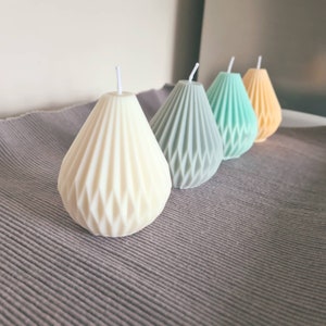 Puede incluir: Cuatro velas con forma de pera con un diseño geométrico. Las velas son de color blanco, gris, azul y amarillo.